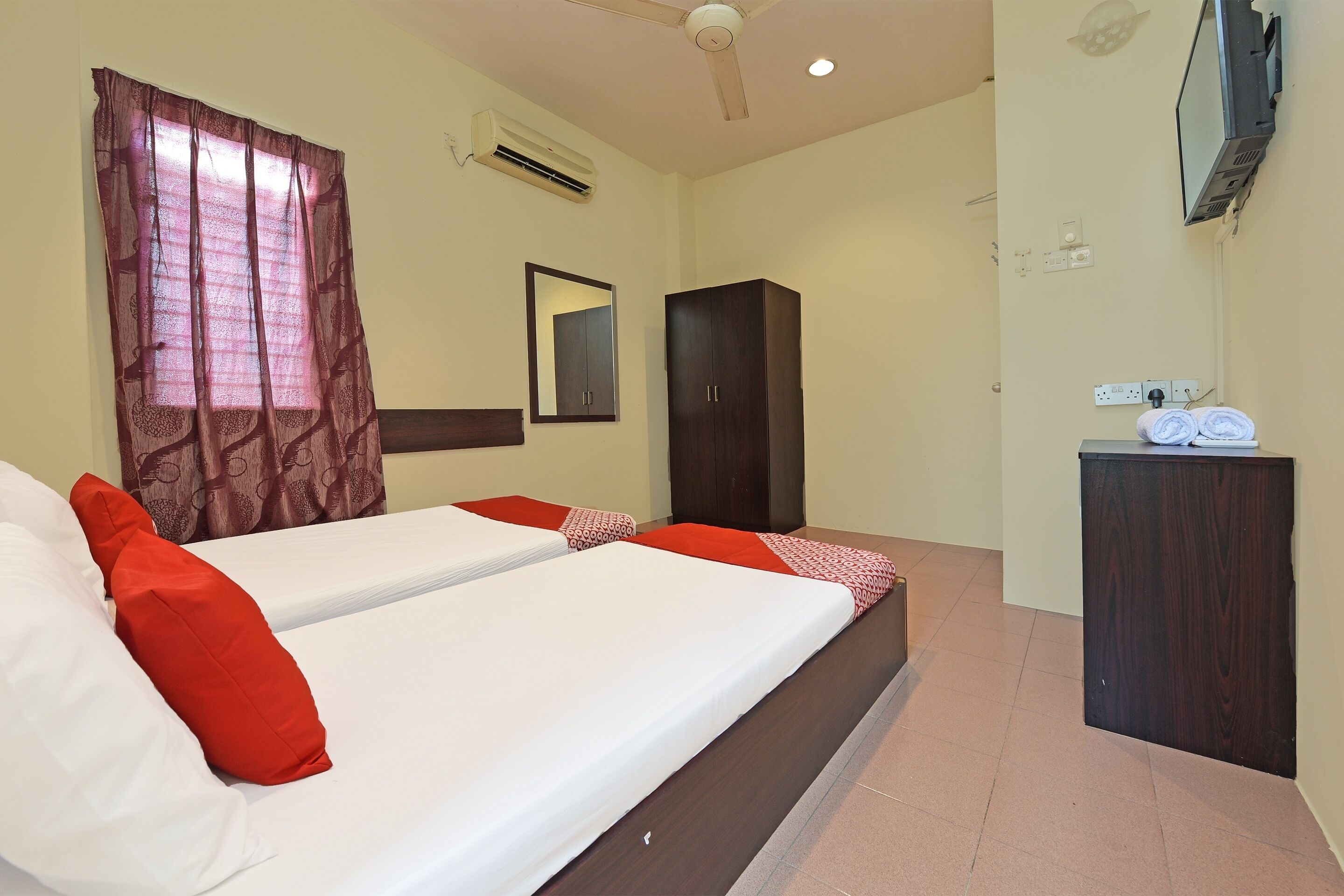 A hotel room with a bed, a wardrobe, a mirror, and a small desk with towels.