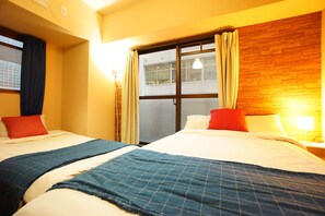 A hotel room with two beds, a wooden headboard, a window with curtains, and a nightstand with a lamp. - Terry's Apartment Shinsaibashi East I G04C (Osaka)
