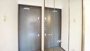 A hallway with two doors, one with a frosted glass panel and the other with a clear glass panel. - Terry's Apartment Shinsaibashi East I G04C (Osaka)