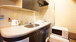 A kitchen with a sink, a kettle, a microwave, and cabinets. - Terry's Apartment Shinsaibashi East I G04C (Osaka)