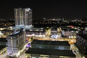 A nighttime cityscape with modern buildings, a busy intersection, and illuminated streets.