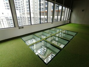 A room with a glass floor, large windows, and a green carpet.