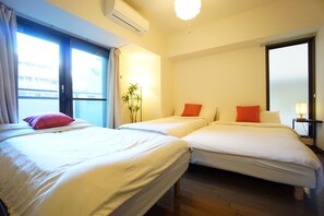 Habitación de hotel con dos camas, una planta en maceta y una ventana con cortinas.