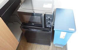 A compact kitchen with a black refrigerator, a microwave, and a blue cabinet. - Terry's Apartment Shinsaibashi East I G07B (Osaka)