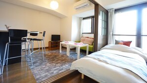 A modern hotel room with a bed, a desk with a chair, a small table, and a sofa. - Terry's Apartment Shinsaibashi East I G07B (Osaka)