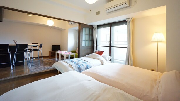 A hotel room with two beds, a desk, and a chair. - Terry's Apartment Shinsaibashi East I G07B (Osaka)