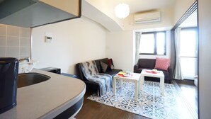 Un espace de vie compact comprenant un coin cuisine, un canapé, une table basse et un tapis à motifs.