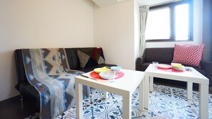 Un salon avec un canapé, deux tables et une fenêtre avec des rideaux.