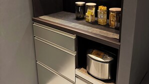 A compact kitchen with a built-in stove, a small countertop, and storage cabinets. - TABISAI Luxe (Fukuoka)