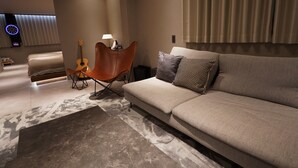 A modern living room with a sofa, a chair, a guitar, and a lamp. - TABISAI Luxe (Fukuoka)