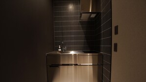 A modern kitchen with stainless steel appliances, a sink, and a ventilation hood. - TABISAI Luxe (Fukuoka)