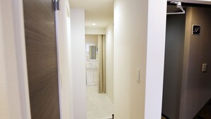 Un couloir doté d’un plancher en bois, de murs blancs et d’une porte donnant sur une salle de bain.