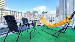 Une terrasse sur le toit avec un hamac jaune, deux chaises et une petite table.