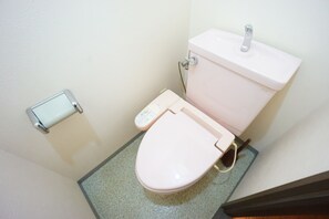 A small bathroom with a white toilet, a white sink, and a toilet paper holder on the wall. - Terry's Apartment Shinsaibashi East I G13B (Osaka)