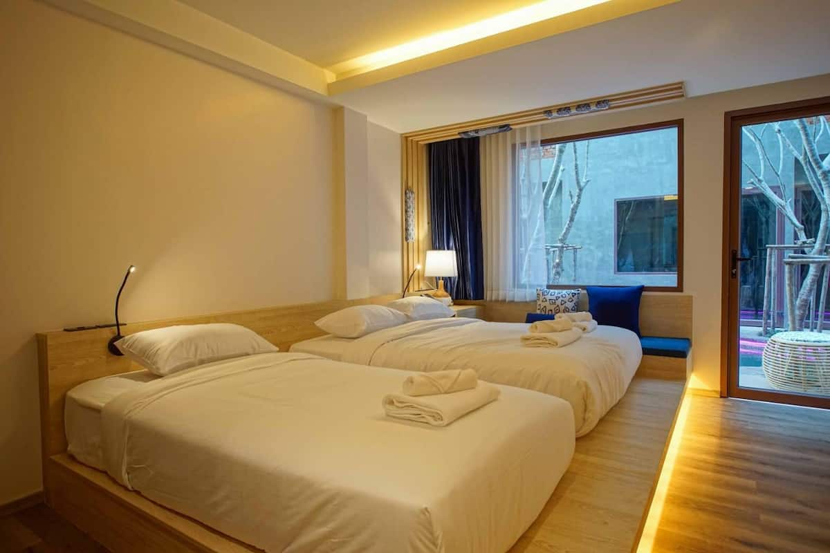 Habitación de hotel con dos camas, un ventanal con vistas y piso de madera.