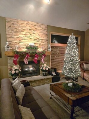 A cozy living room with a fireplace, a Christmas tree, and festive stockings. - 5 BR en suite with firepit, hot tub,and game room. (Galena)