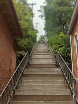 A concrete staircase with metal railings, leading up to a building with a brick facade and arched windows.