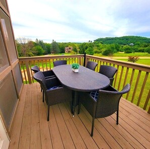 A wooden deck with a round table and six wicker chairs, overlooking a green landscape with trees and a distant house. - 5 BR en suite with firepit, hot tub,and game room. (Galena)