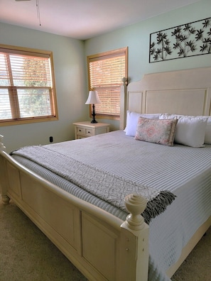 A bedroom with a bed, two windows with blinds, a nightstand with a lamp, and a wall art piece. - 5 BR en suite with firepit, hot tub,and game room. (Galena)