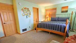 Un dormitorio con cama, una silla, una puerta y un adorno en la pared.