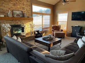 A living room with a fireplace, a television, and a large window.