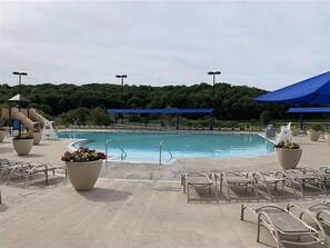 Ein Poolbereich mit Liegestühlen, einer Rutsche und einem blauen Sonnensegel.
