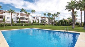 A swimming pool surrounded by palm trees and a building with balconies. - Awesome apartment in Estepona with WiFi (Estepona)