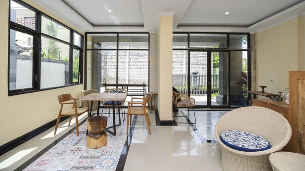 A spacious room with a large dining table, multiple chairs, a wicker sofa, and a patterned rug.