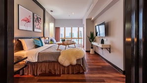 A modern hotel room with a large bed, a TV, a desk, and a window with a city view. - Sunway Resort By Himmel (Petaling Jaya)