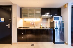 A modern kitchen with black cabinets, a stainless steel refrigerator, and a microwave.