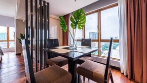 A modern dining area with a black table, four brown chairs, and a large window with curtains. - Sunway Resort By Himmel (Petaling Jaya)