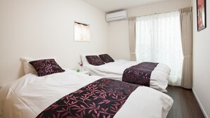 Une chambre d’hôtel avec deux lits, une fenêtre avec des rideaux, un appareil de climatisation et un petit tableau accroché au mur.