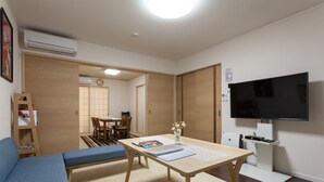 Un espace de vie compact comprenant un canapé, une table à manger, un téléviseur et une petite kitchenette.