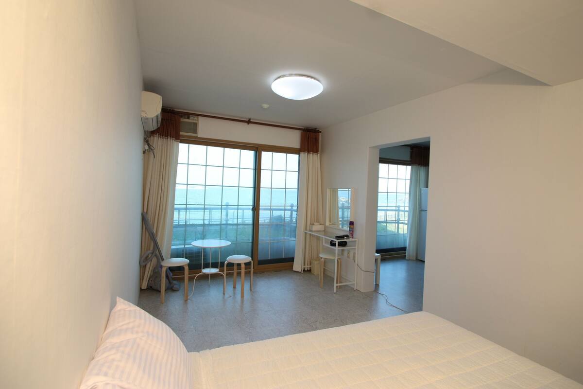 Een hotelkamer met een bed, een bureau, twee stoelen, een tafeltje en uitzicht op het omliggende landschap.