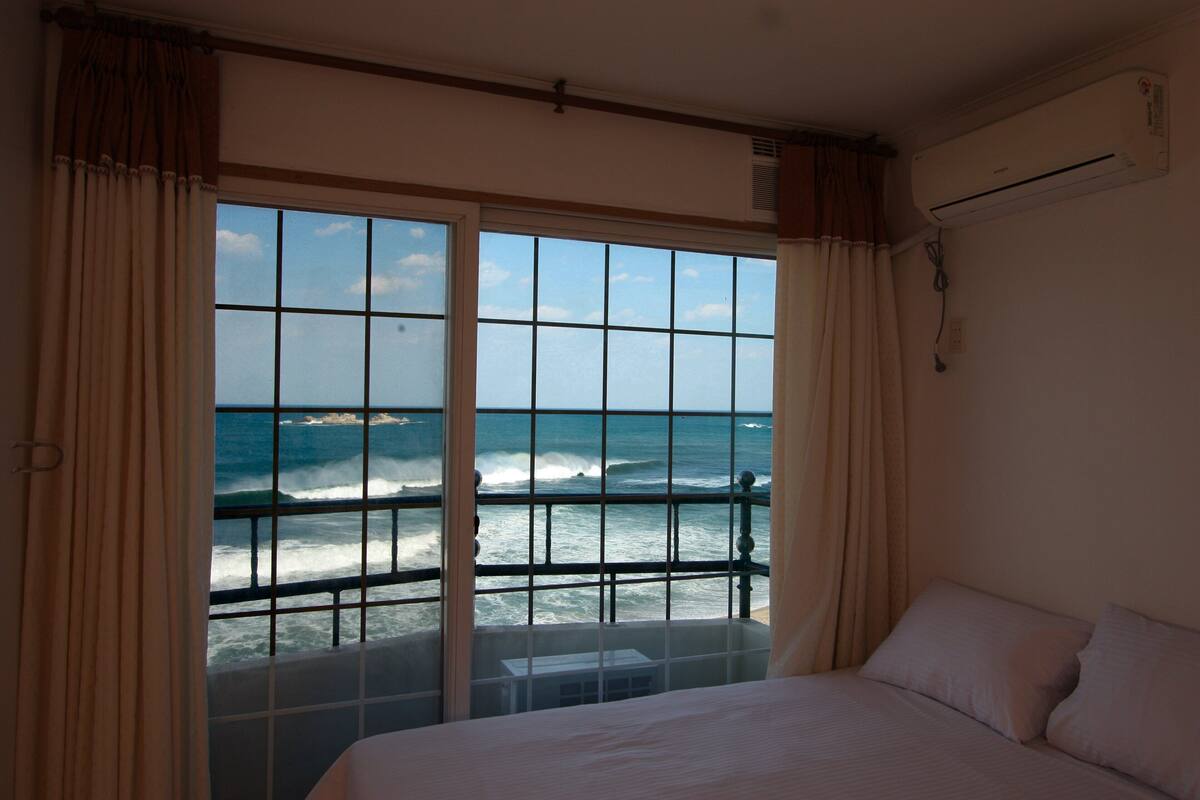 Een hotelkamer met een groot raam en uitzicht op de oceaan.
