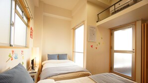 Habitación de hotel con dos camas, un escritorio con computadora, ventana con vista a la ciudad y un mapa en la pared.