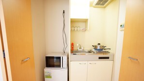 Una cocina compacta con microondas, refrigerador pequeño, pileta y estufa.