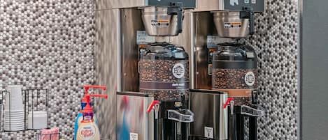 A coffee station with two Bunn coffee machines, a Nestle Coffee Mate dispenser, and a coffee bean grinder.