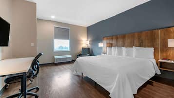 Una habitación de hotel con cama, escritorio, silla y televisor.