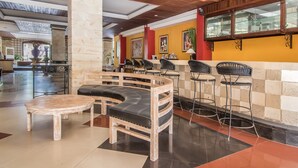 A lobby with a wooden bench, a round table, and black chairs. - Hotel O Maxi Budget (Kuta)