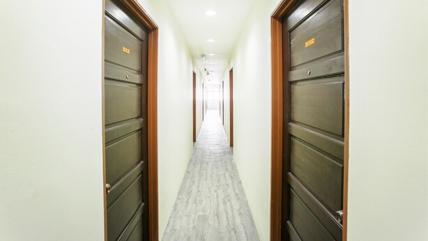A long, narrow hallway with wooden doors on both sides, leading to a bright room at the end. - OYO 822 Zande Motel Kuala Selangor (Kuala Selangor)