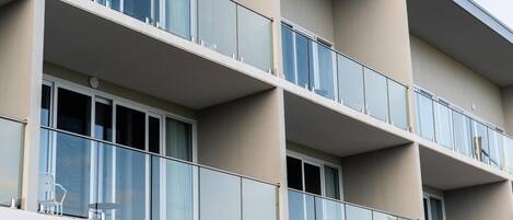 Un immeuble à plusieurs étages doté de balcons, de grandes fenêtres et d’une palette de couleurs neutres.