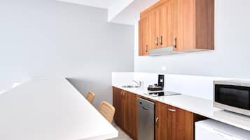 Una cocina moderna con armarios de madera, encimera blanca, lavavajillas y microondas.