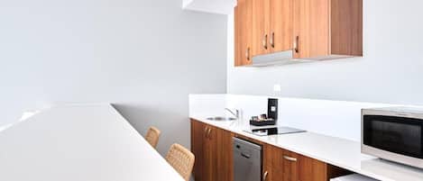 A modern kitchen with wooden cabinets, a white countertop, a dishwasher, and a microwave.
