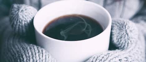Una taza blanca de café con vapor, sobre una superficie de punto.