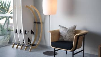 En modern inredning med en flätstol, en golvlampa och surfbrädor lutade mot en vägg.