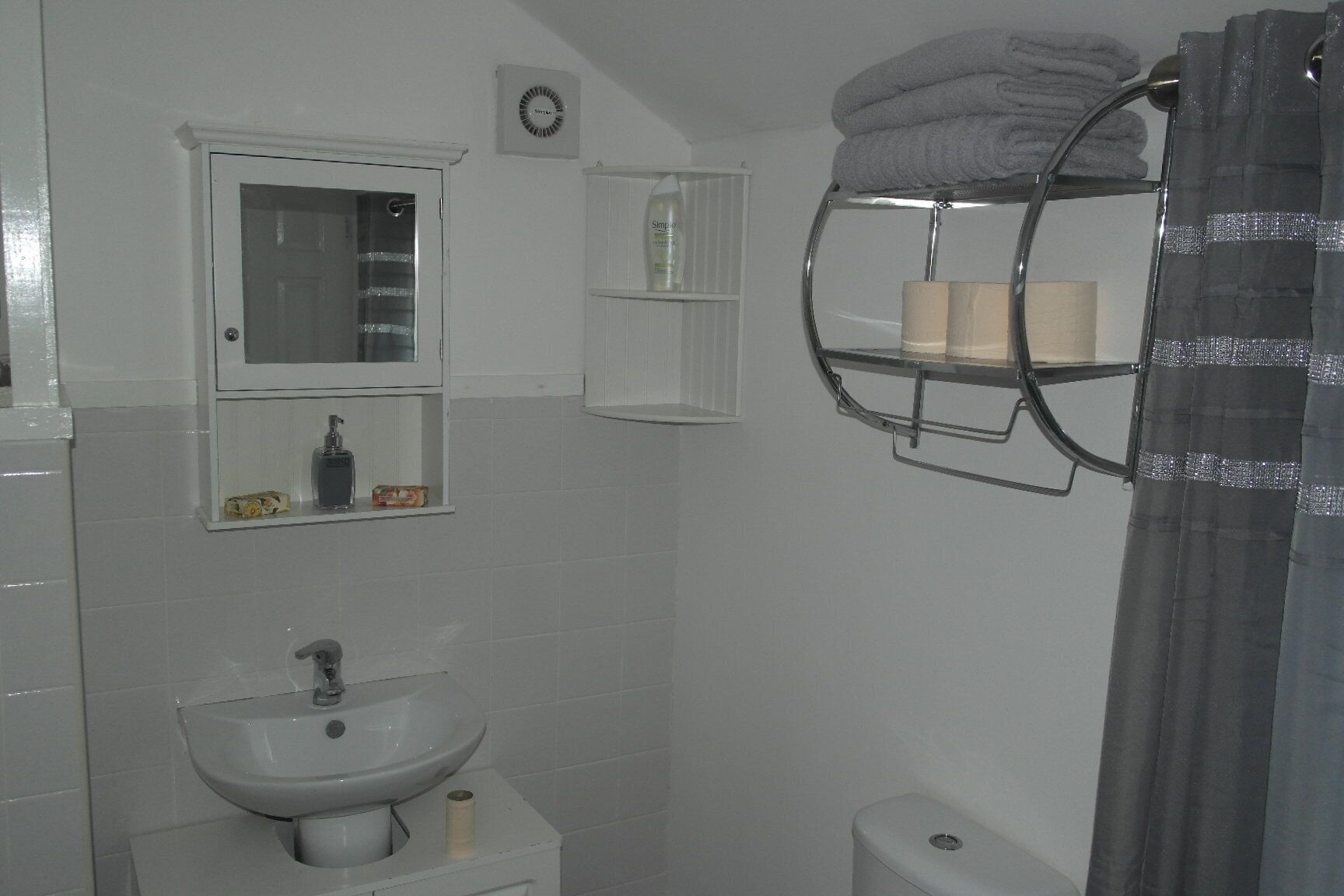 Een badkamer met een wastafel, spiegel en handdoekrek.