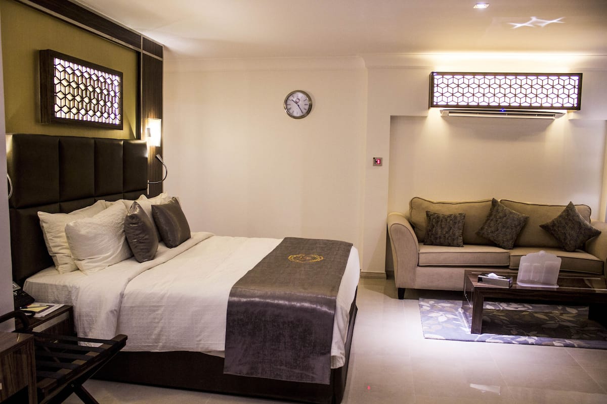Une chambre d’hôtel comprenant un lit, un canapé, une table basse, une horloge et un luminaire décoratif.
