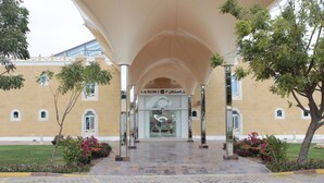 A building entrance with a large canopy, a sign, and a tiled pathway. - Tio Sea Resort (Al Khor)