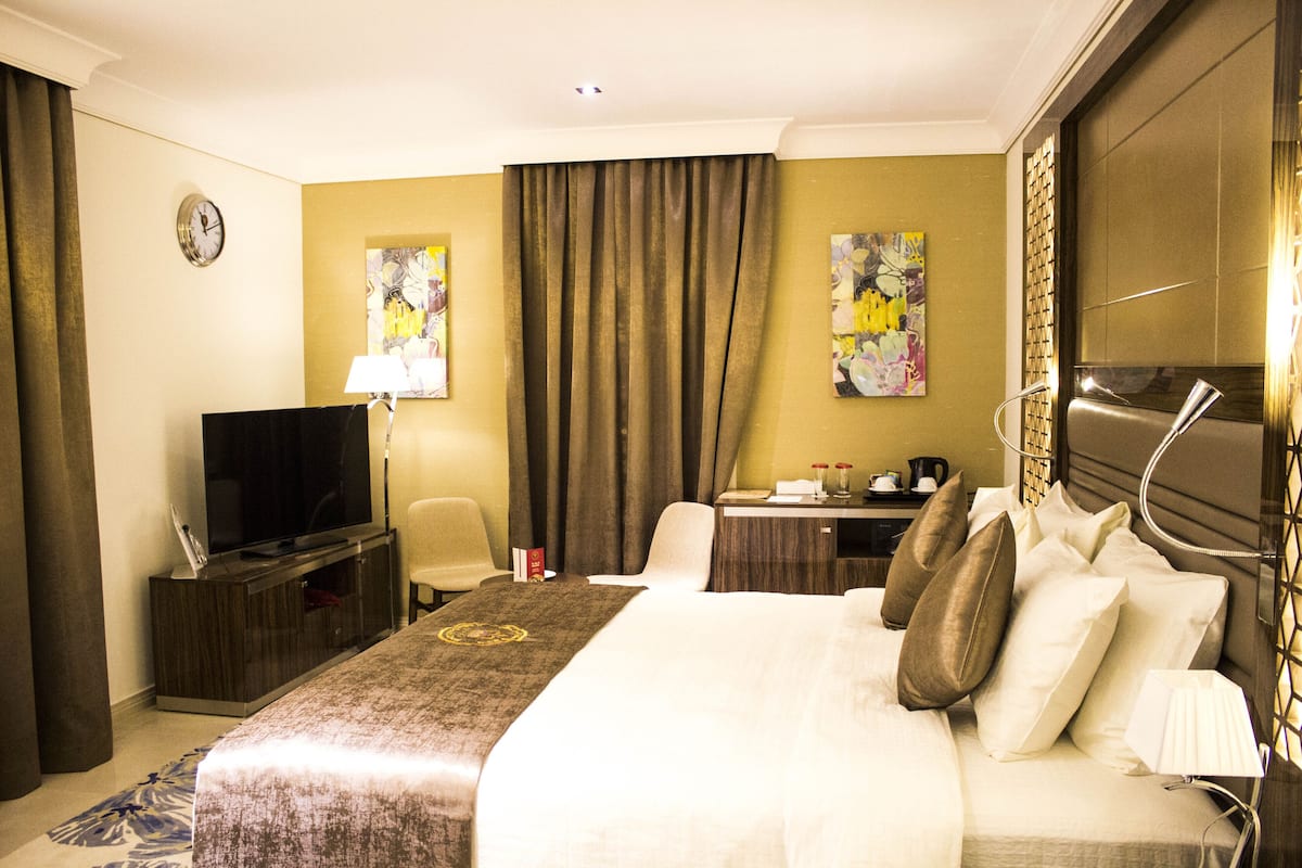 Une chambre d’hôtel avec un grand lit, une télévision, un bureau et une chaise.